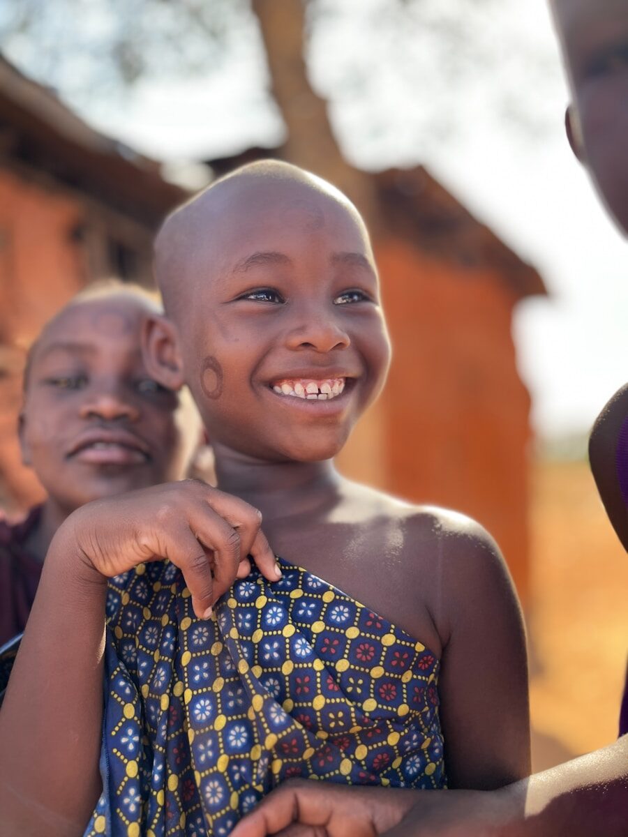 A smiling young child in traditional clothing outdoors attire.
