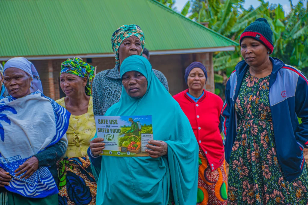 Women of the Wamboma cooperative standing together, one holding the “Safe Use for Safer Food” placard